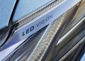 "LED VISION" гэсэн бичвэрийг харуулсан машины гэрлийн ойрын зураг. Гэрэл тусгагч элементүүд болон нарийн ширхэгтэй нарийн хийц бүхий гоёмсог дизайнтай бөгөөд энэ нь мэдэгдэл хийхийг эрэлхийлж буй энтрепренерүүдэд төгс тохирно. Машины гадна тал нь металл цэнхэр өнгөтэй. - Business.MN