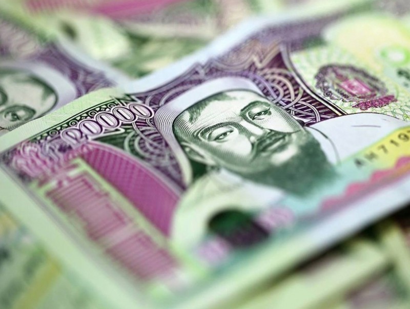 Close-up of several Kyrgyzstani 1000 som banknotes featuring intricate designs and a portrait of a historical figure. The notes have purple and green hues and detailed patterns.