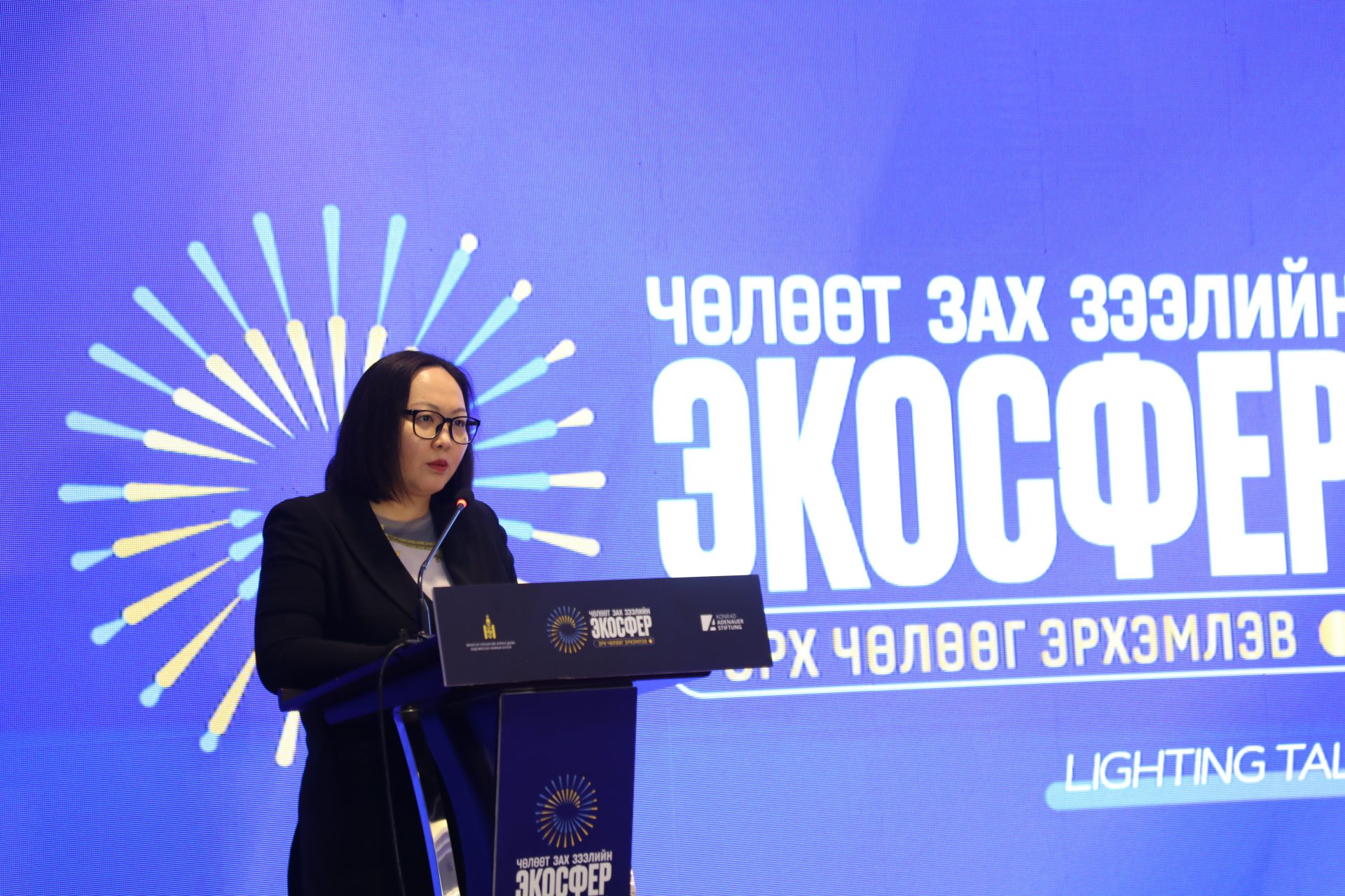 A person is speaking at a podium in front of a blue backdrop with the text "ЭКОСФЕР" and other Cyrillic characters. The event seems to focus on market freedom and human rights. The podium and backdrop have the same logo.