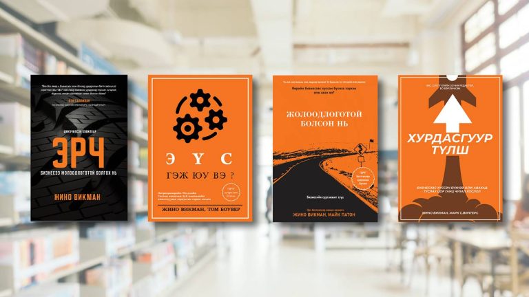 Four captivating books with orange-themed covers are displayed against a blurred library backdrop. The titles, in Cyrillic script, remind us that "Энтерпренер хүн болгон захирал удирдагч байдаггүй" and each features unique graphical elements and icons.