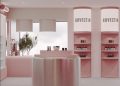 Minimalist pink and white store interior with curved shelves displaying skincare products labeled "Rovectin." A round, central counter and tubular lights hang from the ceiling. A large window shows a view of trees outside.