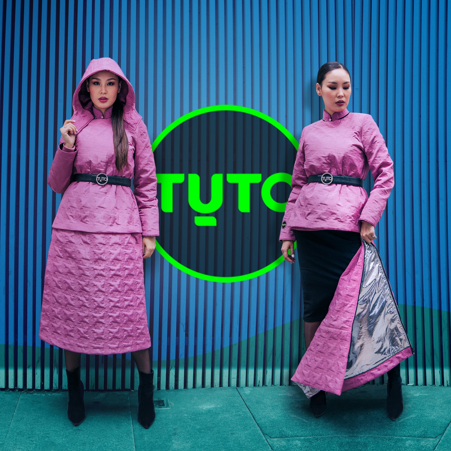 Two women in pink, textured hooded outfits stand in front of a blue wall with a green neon circle behind them. One woman wears knee-high boots, while the other reveals a silver lining of her skirt, paired with ankle boots.