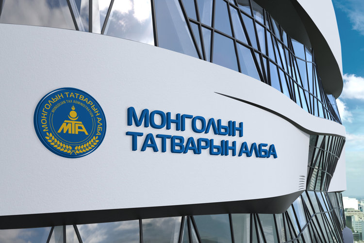 The image shows a modern curved building with reflective glass windows. On the building's facade, there's a circular blue and gold emblem next to Mongolian text in blue. The sky is partly cloudy.